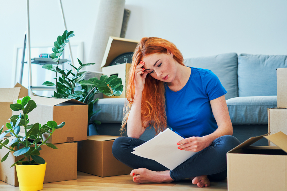 woman in blue shirt sitting down stressed about moving and packing.